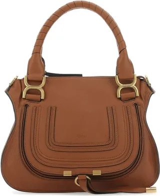 Handbag realized in pebble calf leather characterized by embossed logo on the flap enriched by tonal leather patches at the front.