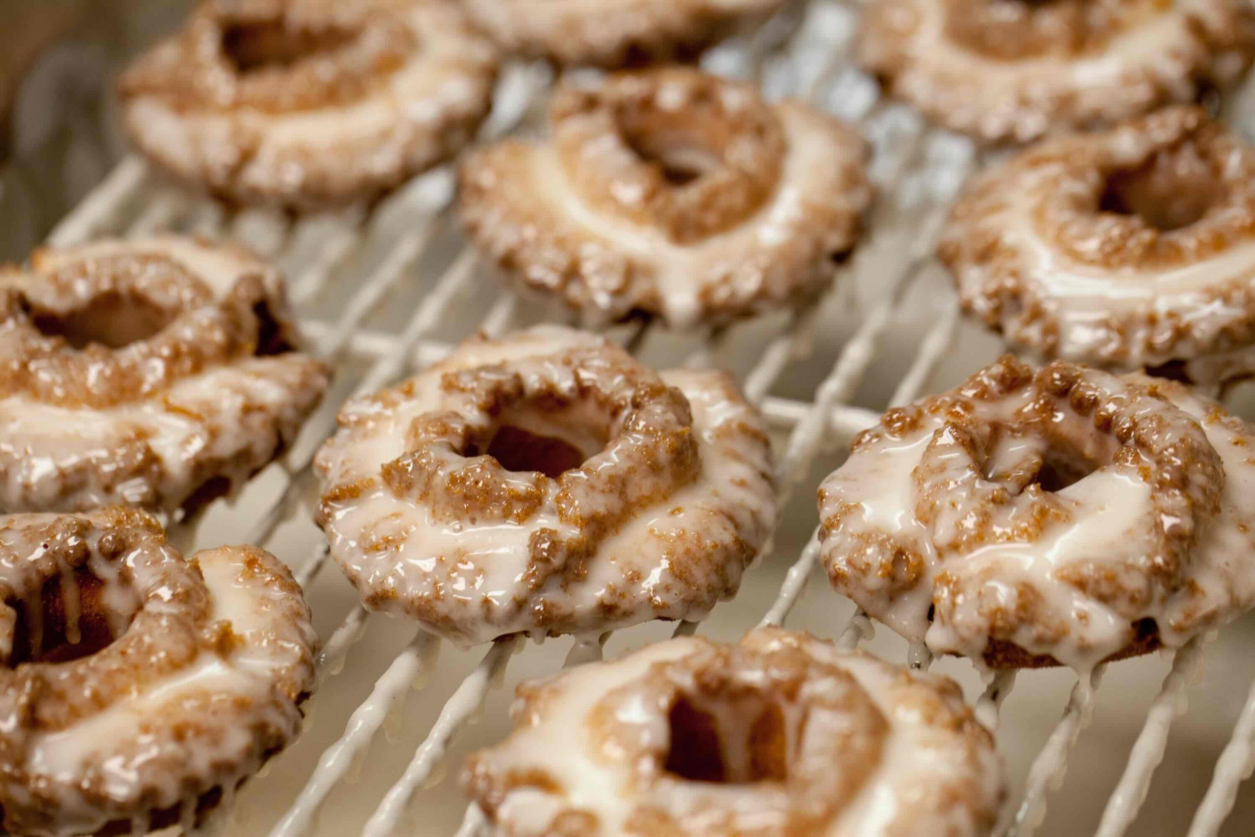 Freshly glazed Old Fashioned Donuts on a sheet rack.