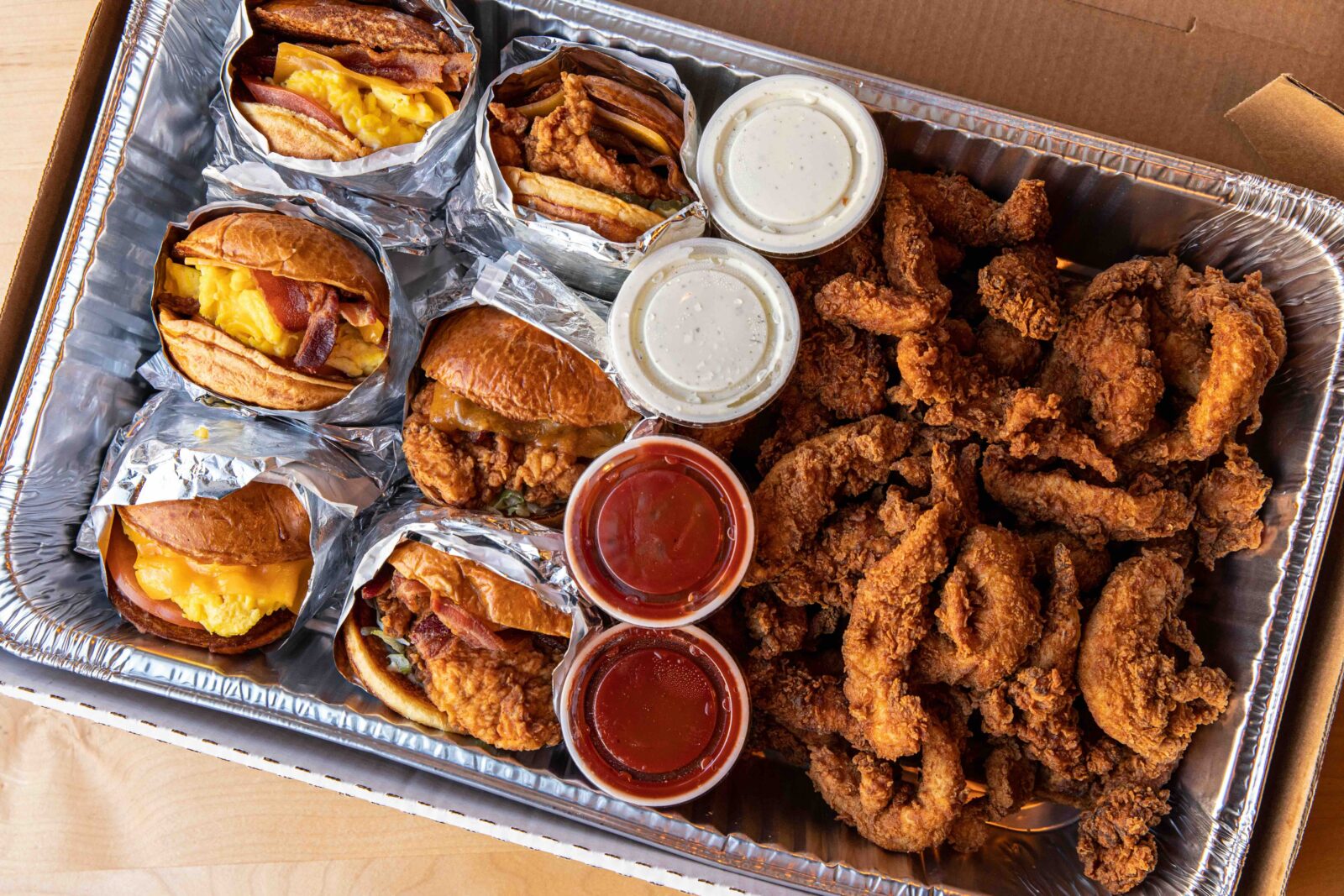 Catering pan with breakfast sandwiches, chicken sandwiches, sauce and chicken 