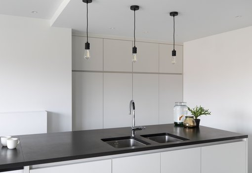 Keuken met kiezelgrijze kastdeuren met zwart werkblad in natuursteen