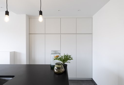 Keuken met kiezelgrijze kastdeuren met zwart werkblad in natuursteen