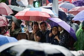 People stands in the rain to watch the military march and parade...