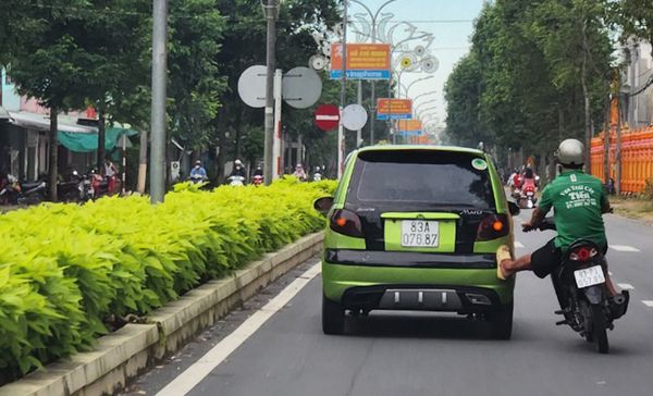 In Vietnam, moving motorcyclist pushes stalled car to repair shop with his leg