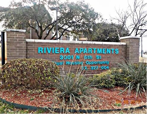 Outdoor sign with landscapint with text that reads Riviera Apartments 3001 N. 6th St..