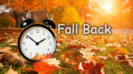 Daylight Savings Fall Back text. An alarm clock in a field of leaves.