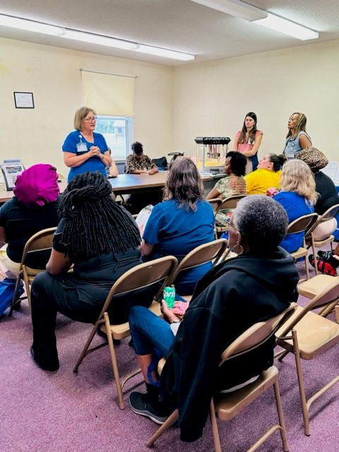 A medical professional addresses a group of people.