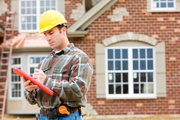 A man in a hard hat looks at clipboard.