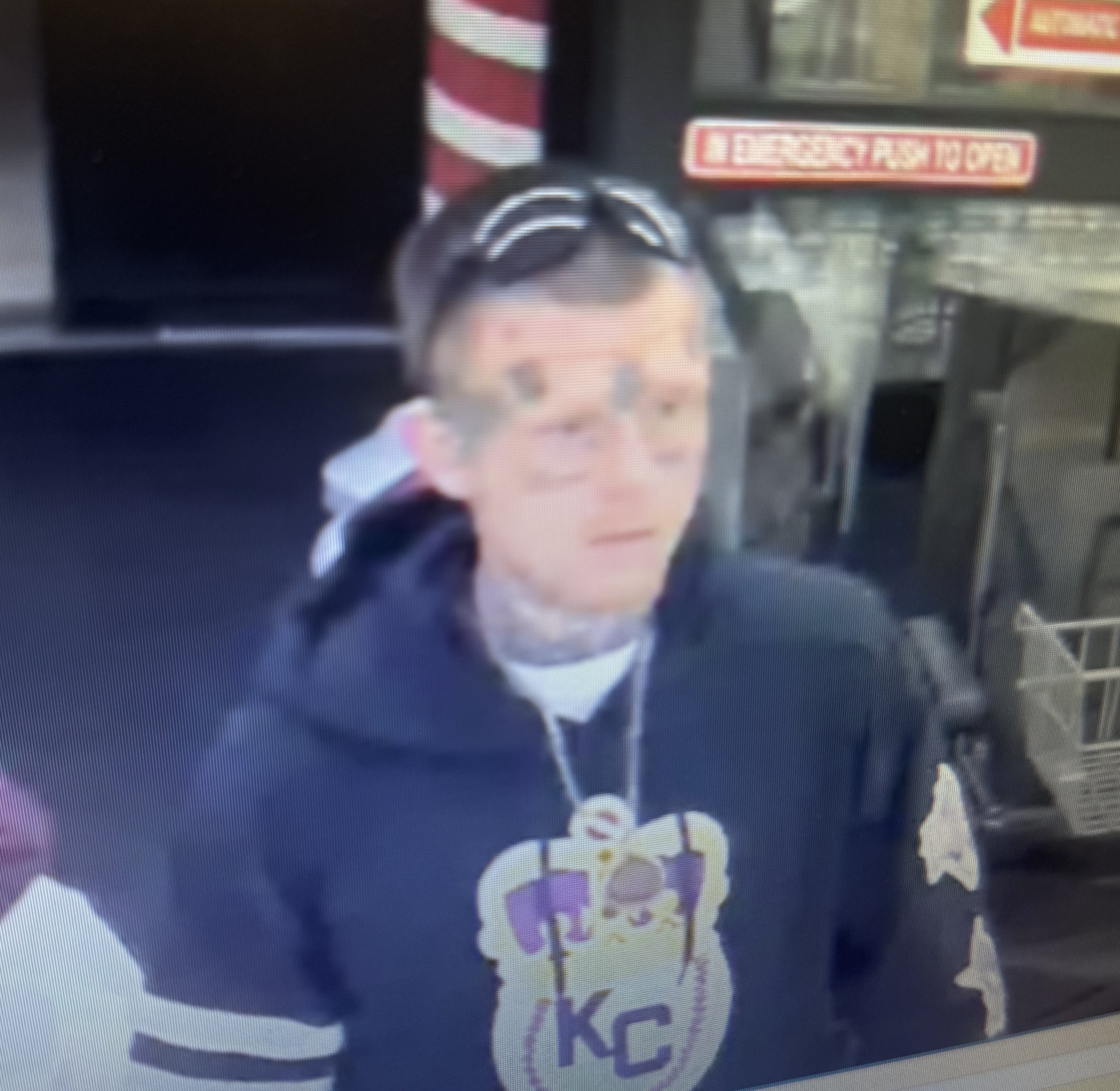 White male with facial tattoos, black sunglasses, and a black hoodie.