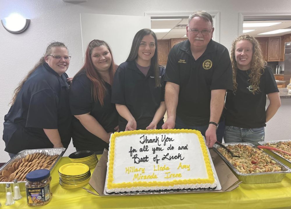 Four women next to the Sheriff and a cake.