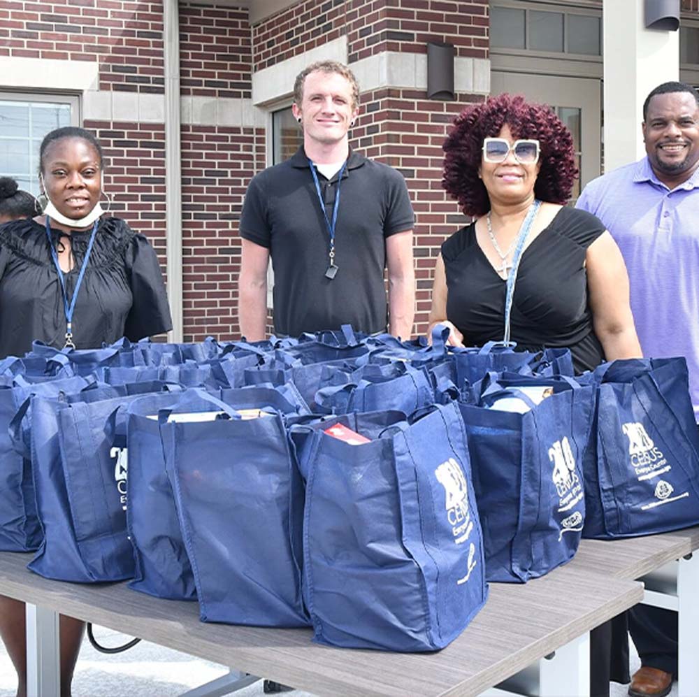 Individuals standing behind multiple bags with supplies.