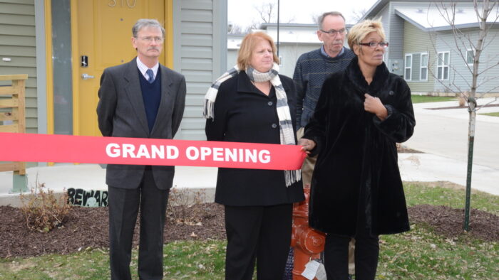 Individuals holding a grand opening ribbon.