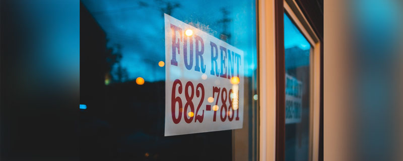 A for rent sign hanging on a window.