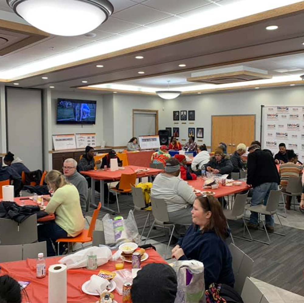 Various individuals sitting at tables in a large room.