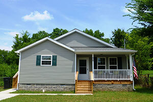 Front view of a single story home with trees and the sky in the background.