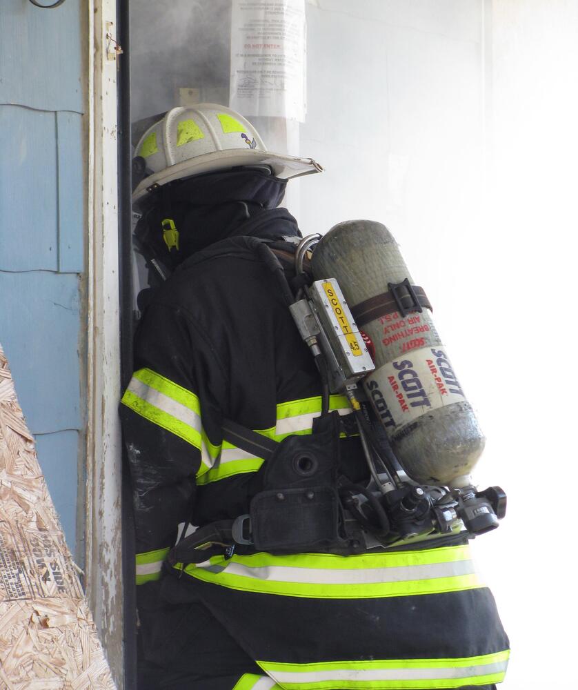 Firefighter in full gear entering a building.