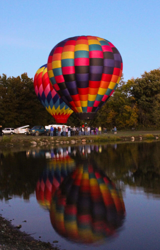 Two hot air balloons during the day near the lake.