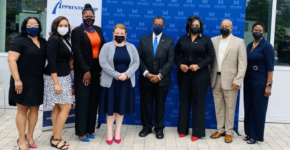 A group of individuals posing in front of a Midlands Apprenticeship backdrop.