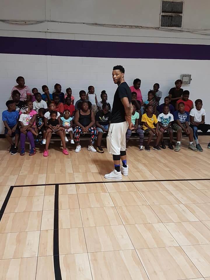 Students sitting on bleachers while the coach talks to them.