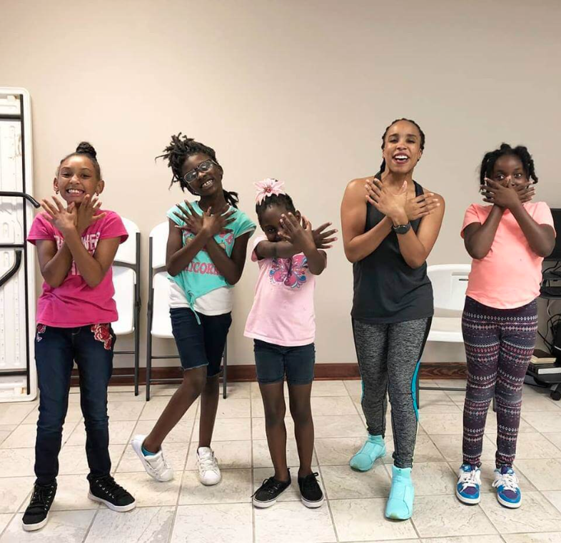 Instructor and students posing with their hands forming a butterfly shape.