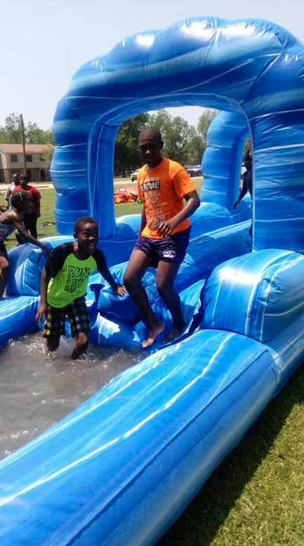 Child standing on the end of a giant inflatable water slide.