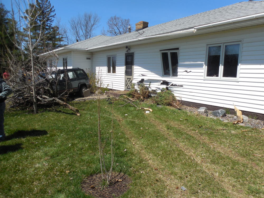home with the siding scraped off and a tree knocked down after a vehicle hit the home