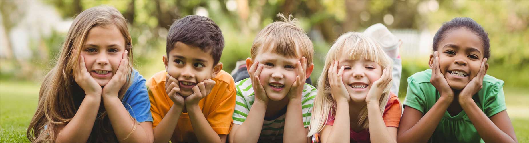 Five smiling children laying in the grass