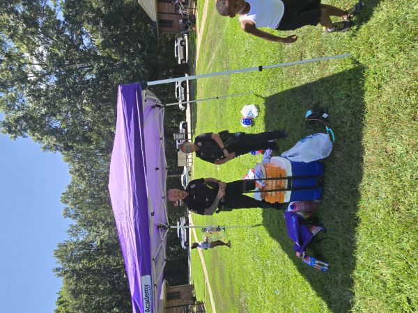 Two officers standing under a tent, watching kids play.