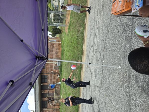 Two officers playing ball with kids.
