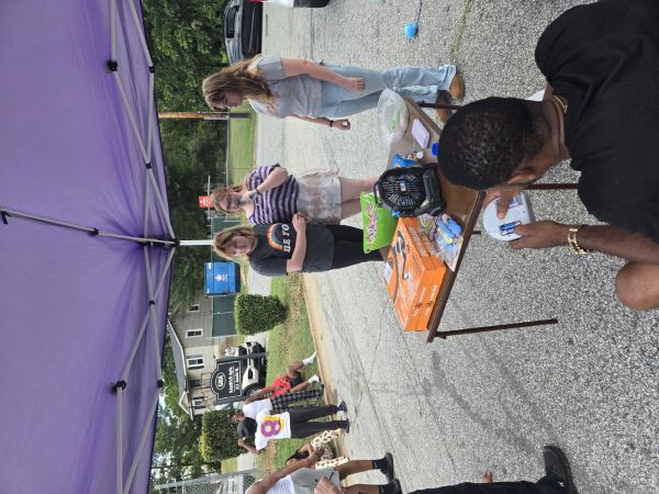 People standing around eating and talking under a tent.