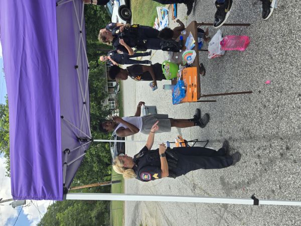 A female officer pointing out food on a table to kids.