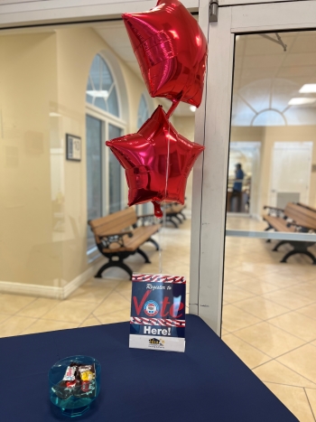 A bowl of candy on a table with voter registration flyer and balloons.