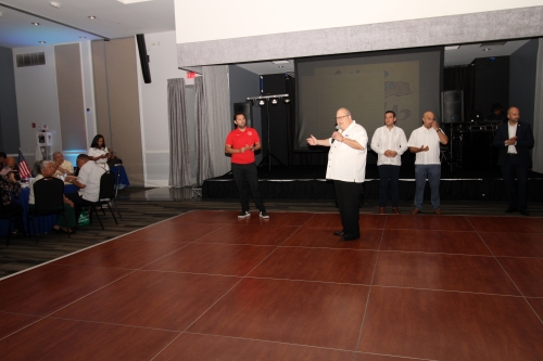 A man standing in the middle of the dance floor with a microphone.