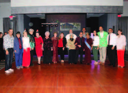 Individuals standing in a room dressed in Christmas clothes.