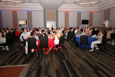 Groups of people sitting at tables at the Fourth of July party.