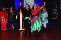 Individuals waving at others at a Halloween party.