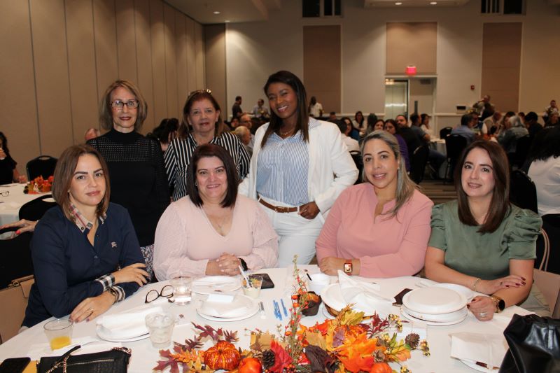 Group of women around a table posing for a picture. 