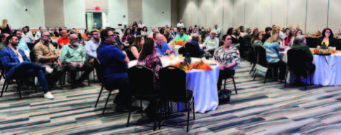 A group of people sitting at tables in a large room.