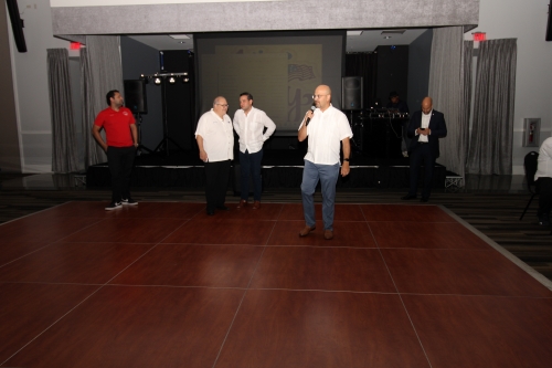 Man standing on the dance floor talking into the microphone.