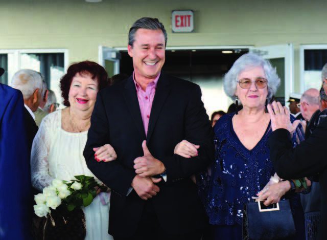 A man walking down the aisle with two ladies.