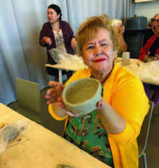 A woman showing off her bowl made out of clay.