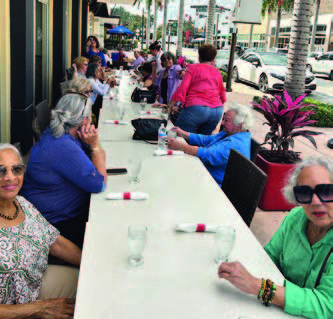 Many individuals sitting at a table outside.