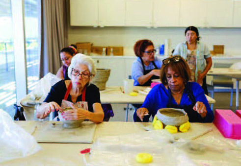 Two women sitting next to each other crafting.