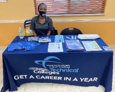 Woman sitting at MDCPS Technical Colleges table. 