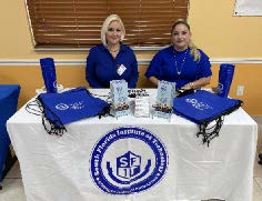 Two women sitting at the South Florida Institute of Technology table. 