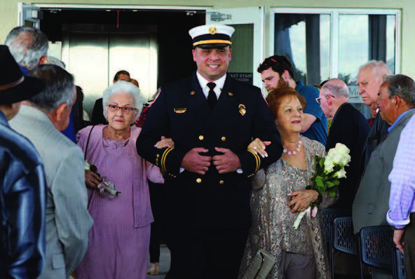 Two women walking down the aisle with a man.