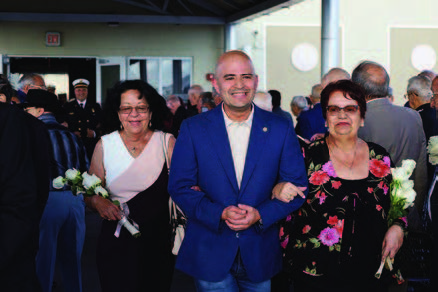 A man in a blue suit walking with two ladies.