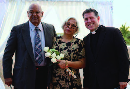 A woman holding flowers next to a man and the marriage officiant.