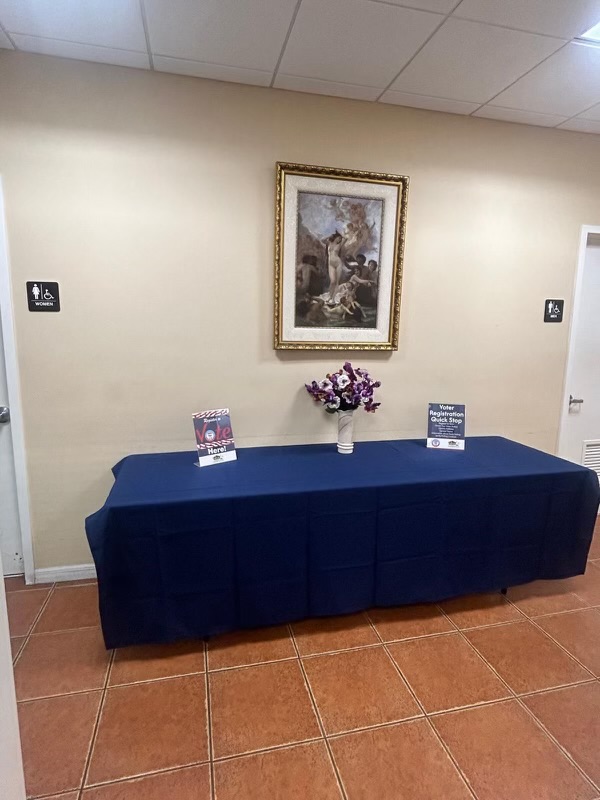 Table with purple flowers and information at the national voting day event.