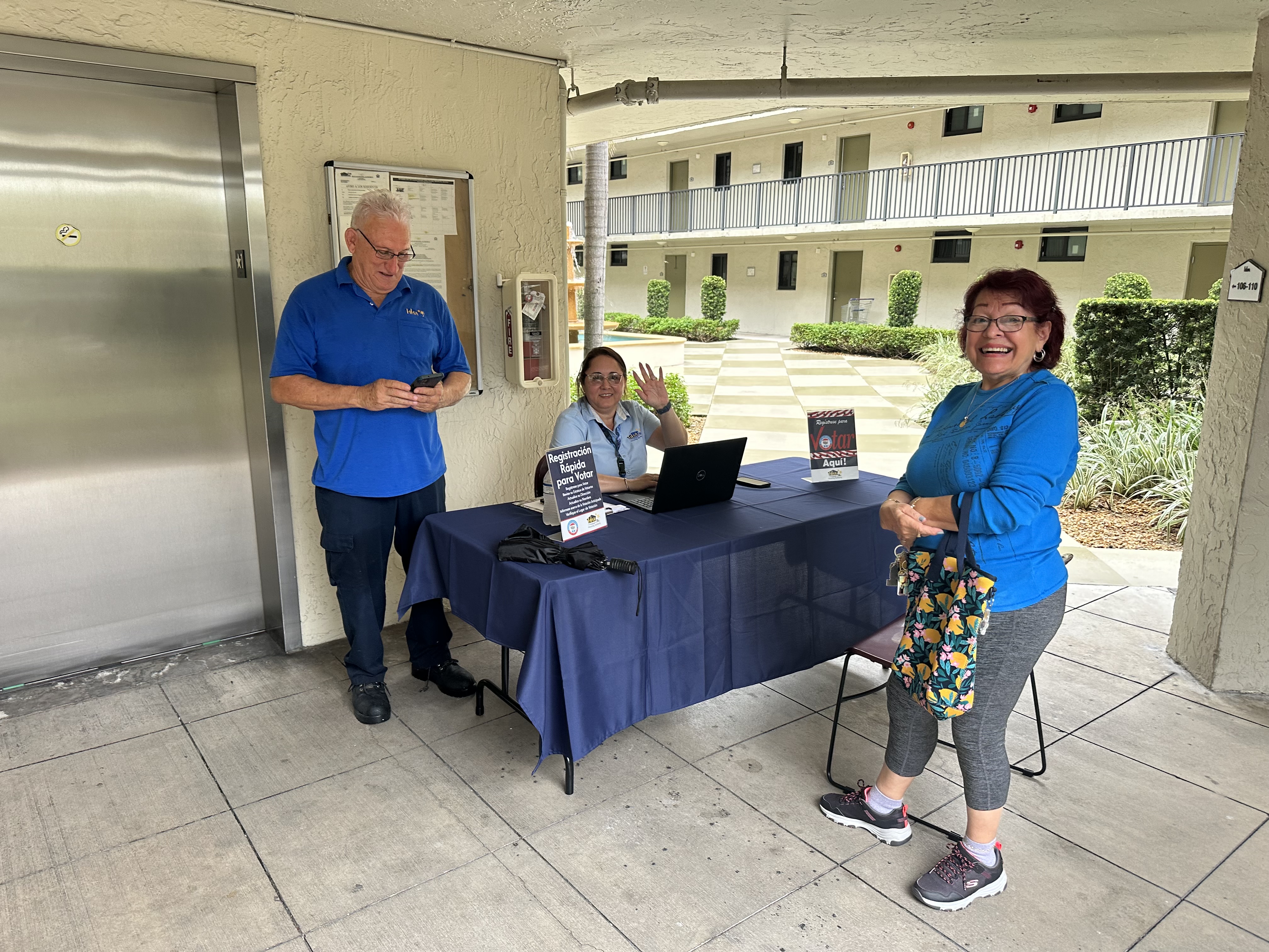 people at a table outside registering to vote.