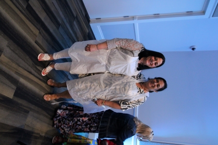two ladies in aprons standing next to each other.